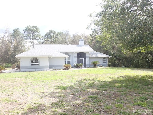 single story home with stucco siding, a chimney, and a front lawn