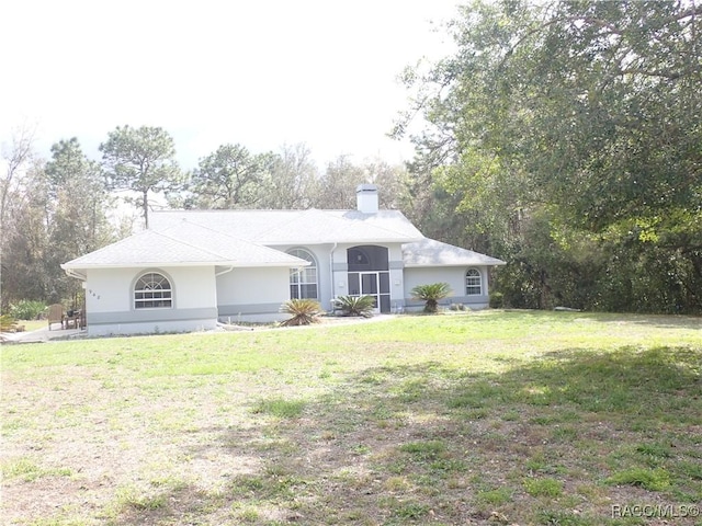 single story home with stucco siding, a chimney, and a front lawn