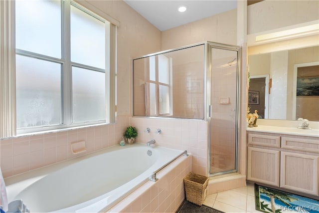 bathroom featuring plus walk in shower, vanity, tile patterned flooring, and a healthy amount of sunlight