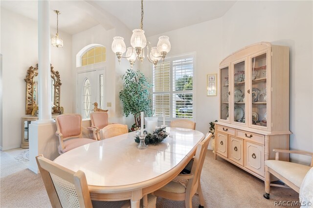 carpeted dining room featuring decorative columns, a chandelier, and lofted ceiling