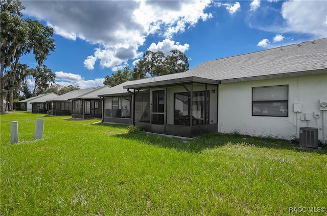 rear view of house featuring central AC unit, a lawn, and a sunroom