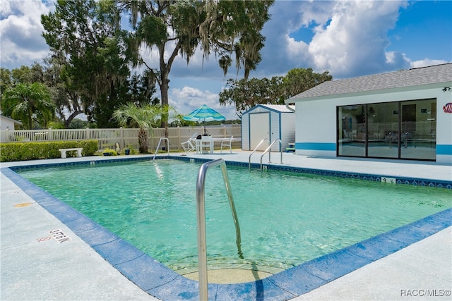 view of pool with a patio and a storage shed