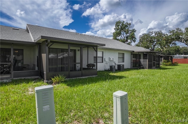 rear view of property with a sunroom, central air condition unit, and a lawn