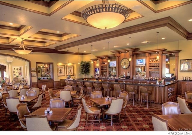 dining room with beam ceiling, wet bar, crown molding, dark colored carpet, and coffered ceiling