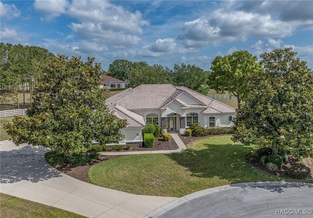 view of front of house with stucco siding, a tiled roof, and a front yard