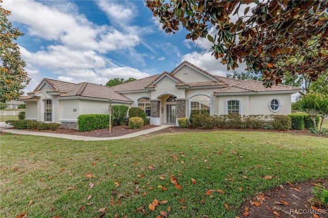 mediterranean / spanish-style home with a tiled roof, stucco siding, and a front yard