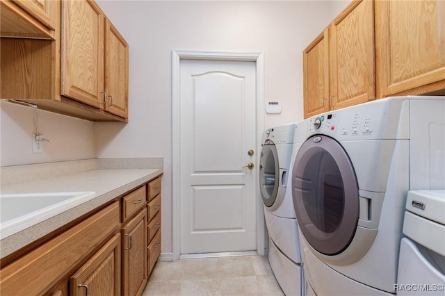 washroom featuring light tile patterned floors, a sink, cabinet space, and washer and clothes dryer