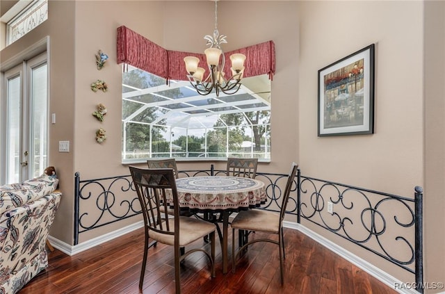 dining space with an inviting chandelier, a sunroom, baseboards, and wood finished floors