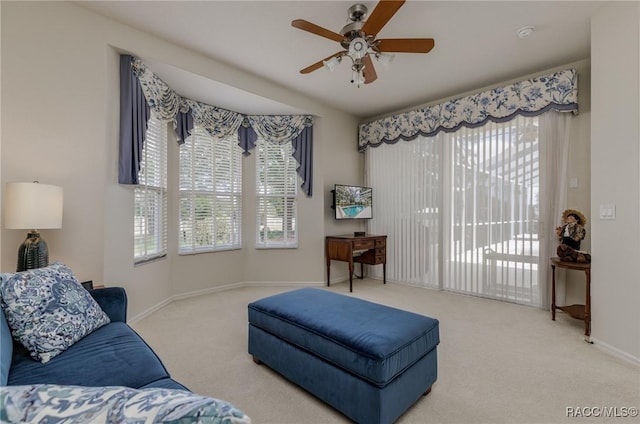 carpeted living room featuring a ceiling fan, baseboards, and a healthy amount of sunlight