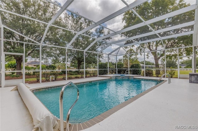 pool with a patio, an in ground hot tub, and glass enclosure