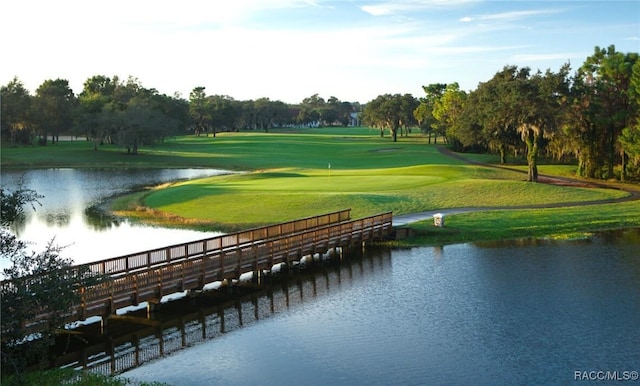 view of community featuring a water view, golf course view, and a lawn