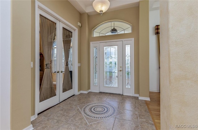 foyer featuring baseboards, french doors, and tile patterned floors