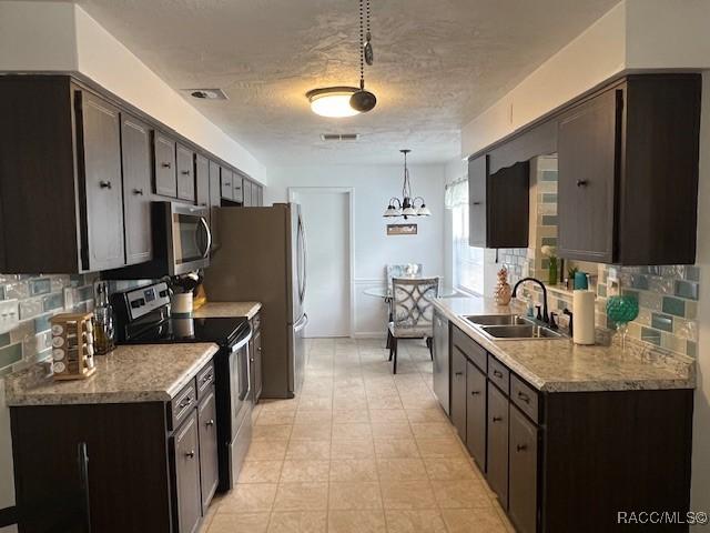 kitchen featuring sink, appliances with stainless steel finishes, dark brown cabinetry, tasteful backsplash, and decorative light fixtures