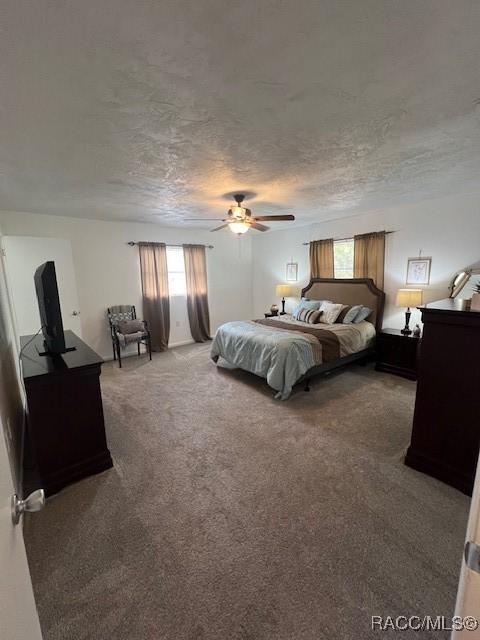 carpeted bedroom with ceiling fan and a textured ceiling