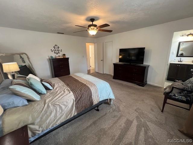 carpeted bedroom featuring a textured ceiling, ceiling fan, and ensuite bath