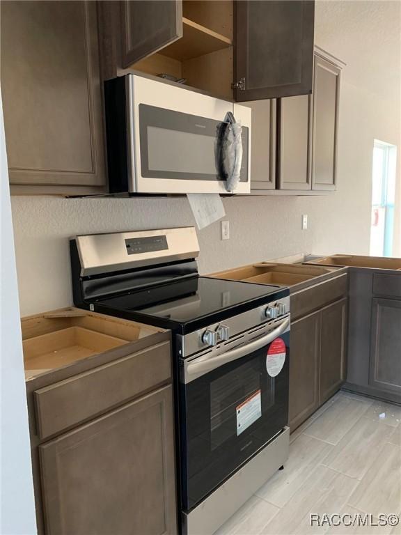 kitchen with dark brown cabinetry and appliances with stainless steel finishes