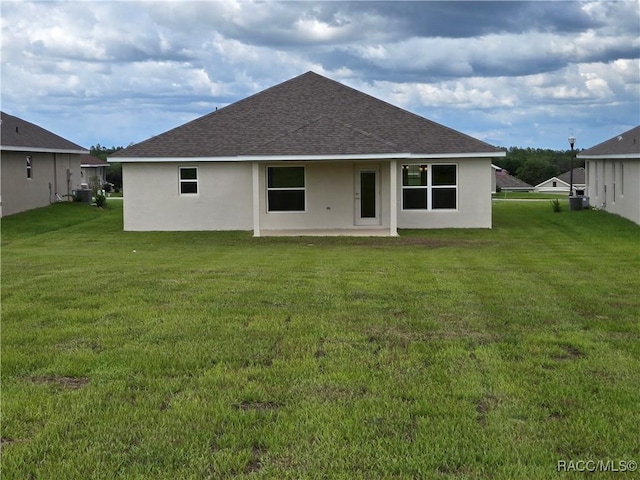348 W Rexford Dr, Beverly Hills, FL 34465 - rear view of house with roof with shingles, stucco siding, a patio area, and a lawn