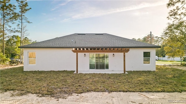 back of house with a pergola, a yard, and stucco siding