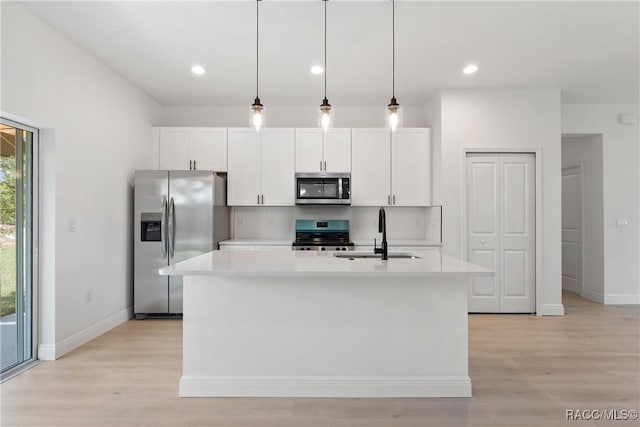 kitchen featuring a sink, white cabinets, appliances with stainless steel finishes, and baseboards