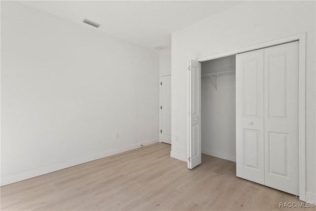 unfurnished bedroom with a closet, visible vents, baseboards, and light wood-type flooring