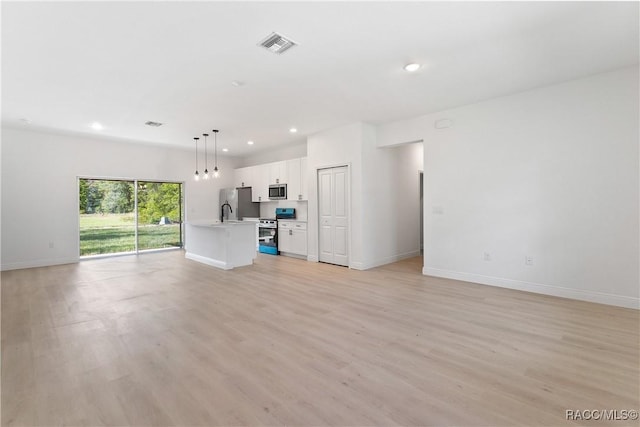 unfurnished living room with recessed lighting, light wood-style floors, a sink, baseboards, and visible vents