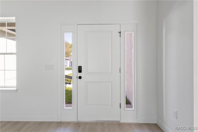 foyer entrance with baseboards, a healthy amount of sunlight, and light wood finished floors