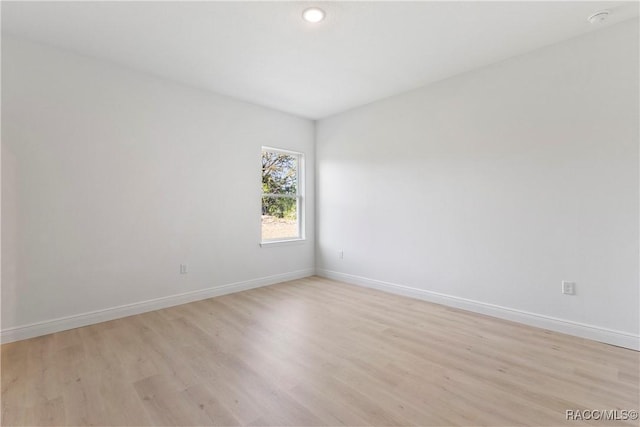 spare room featuring light wood finished floors and baseboards