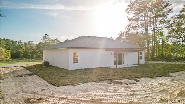 back of house featuring stucco siding, cooling unit, and a yard