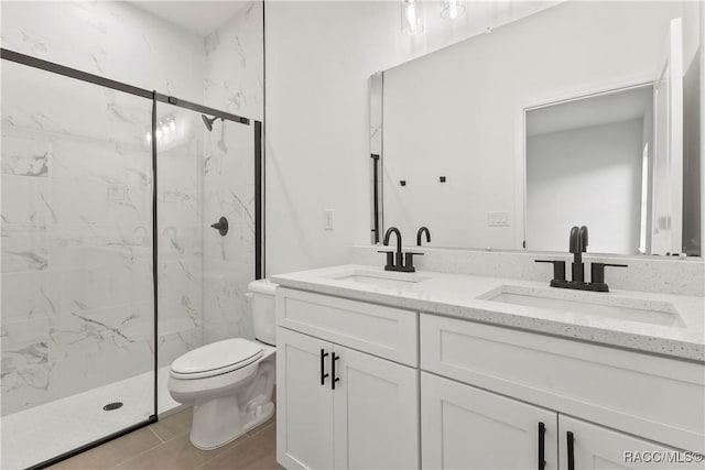full bath featuring toilet, a marble finish shower, a sink, and double vanity