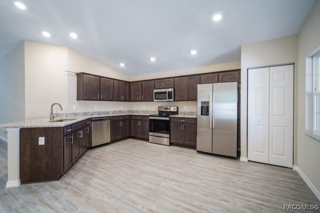 kitchen featuring kitchen peninsula, appliances with stainless steel finishes, light stone countertops, sink, and light hardwood / wood-style flooring