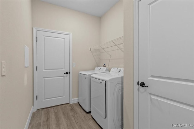 laundry area with washing machine and clothes dryer and light hardwood / wood-style floors