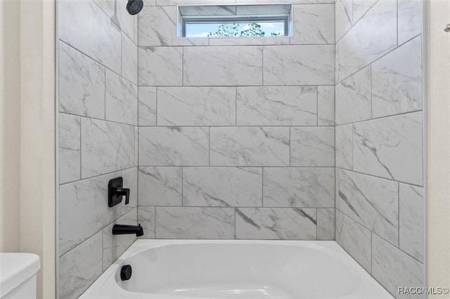 bathroom with tiled shower / bath combo and toilet