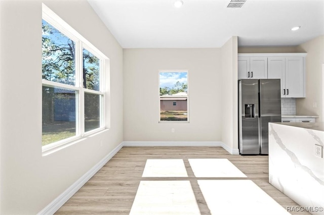 kitchen with white cabinetry, decorative backsplash, stainless steel fridge with ice dispenser, and light hardwood / wood-style floors