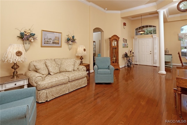 living room with a high ceiling, hardwood / wood-style flooring, decorative columns, and ornamental molding