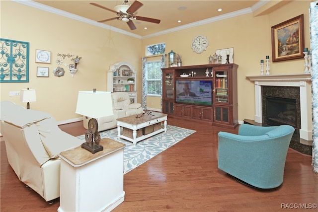 living room featuring hardwood / wood-style flooring, ceiling fan, crown molding, and a premium fireplace