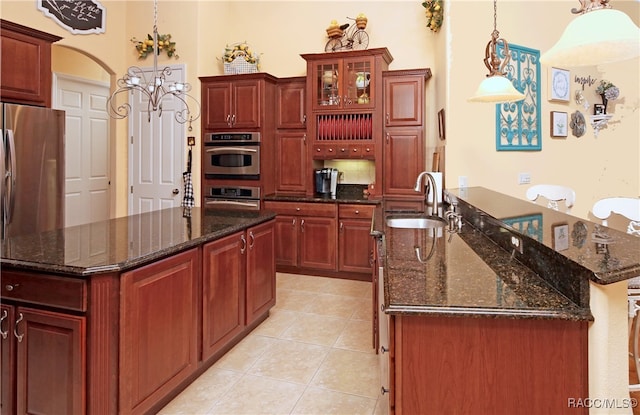 kitchen with a kitchen island with sink, sink, oven, and light tile patterned floors