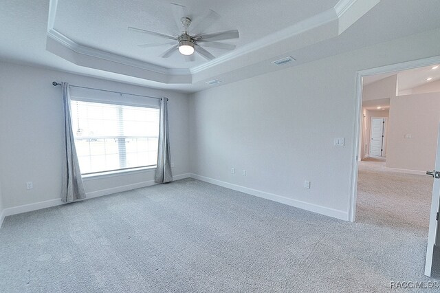 unfurnished room with a tray ceiling, light carpet, crown molding, and ceiling fan