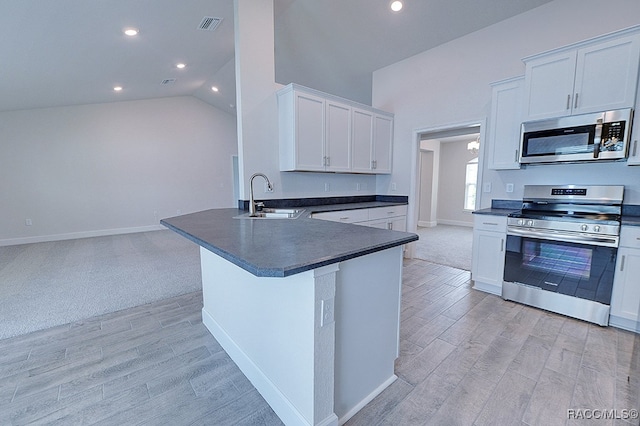 kitchen featuring sink, light hardwood / wood-style flooring, vaulted ceiling, white cabinetry, and stainless steel appliances