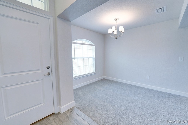 entryway with a notable chandelier, a textured ceiling, and light hardwood / wood-style flooring