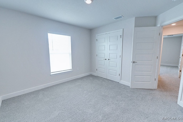 unfurnished bedroom featuring light carpet and a closet