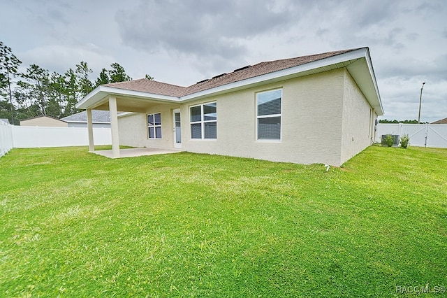 rear view of property with a lawn, a patio area, and central air condition unit