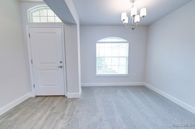 empty room with an inviting chandelier and light hardwood / wood-style flooring