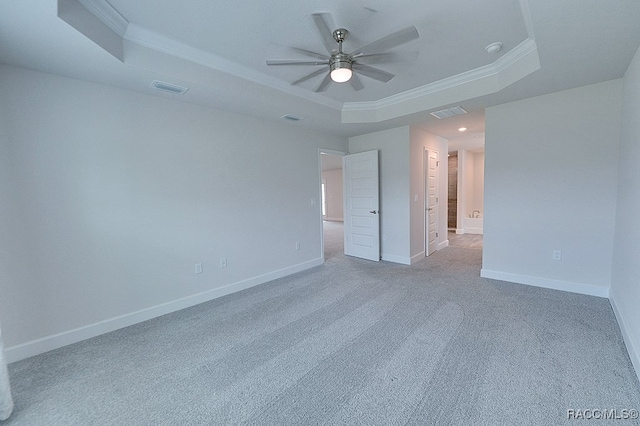 unfurnished bedroom featuring a raised ceiling, ceiling fan, crown molding, and carpet