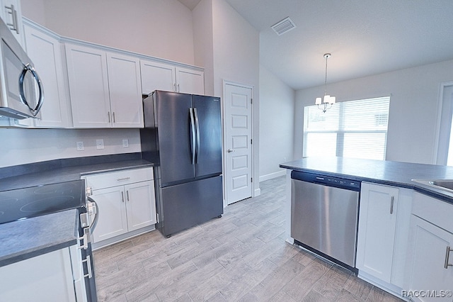 kitchen featuring appliances with stainless steel finishes, pendant lighting, an inviting chandelier, light hardwood / wood-style floors, and white cabinetry