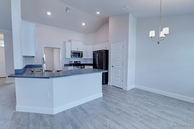 kitchen featuring kitchen peninsula, stainless steel appliances, sink, white cabinets, and hanging light fixtures