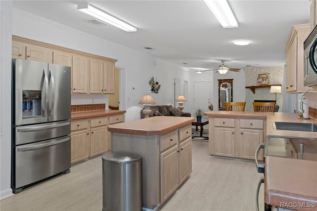 kitchen with stainless steel appliances, light hardwood / wood-style floors, light brown cabinets, and a center island