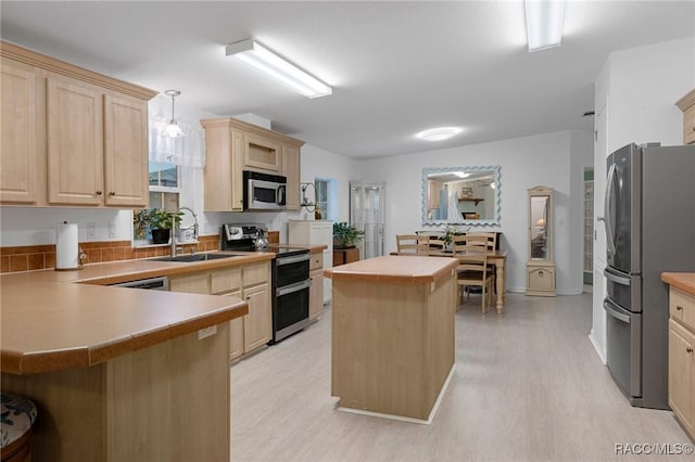 kitchen with pendant lighting, a center island, light brown cabinets, appliances with stainless steel finishes, and sink