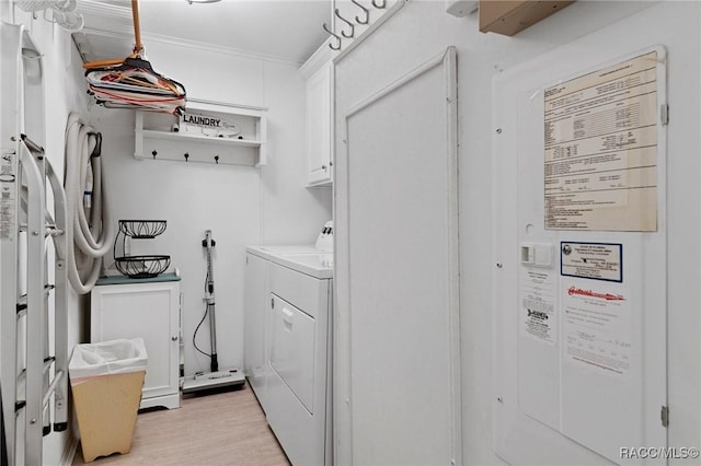 laundry area featuring washer and dryer, cabinets, and light wood-type flooring