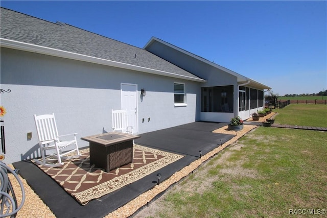 view of patio / terrace with an outdoor fire pit and a sunroom