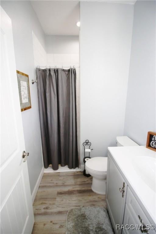 full bath featuring a shower with curtain, toilet, wood finished floors, and vanity